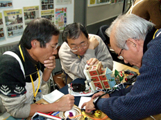 写真：浜松科学館で修理をする岡田さんと会員の皆さん